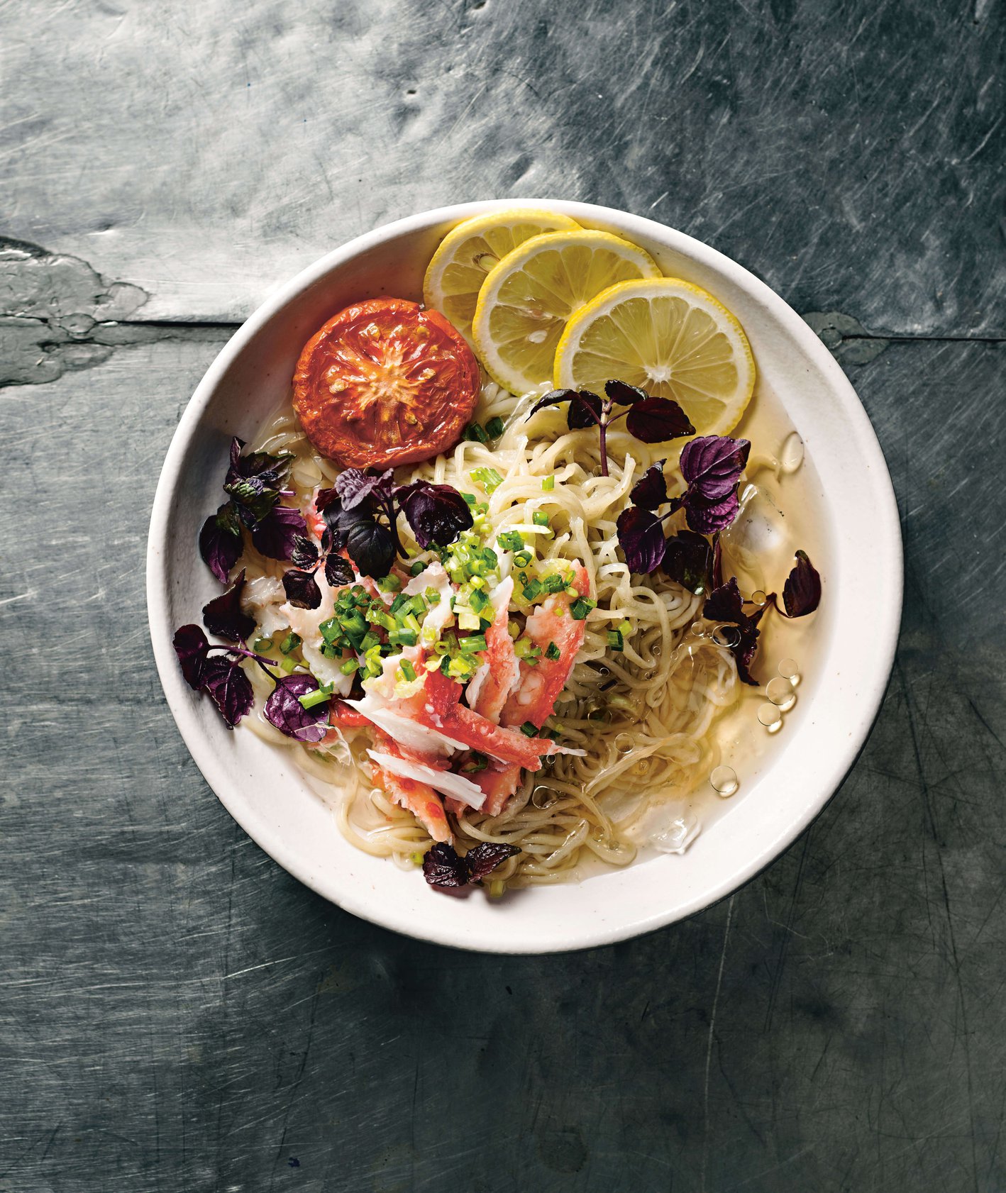 Miska z cold dashi ramen, z krabem, pieczonymi pomidorami, cytryną i ziołami.